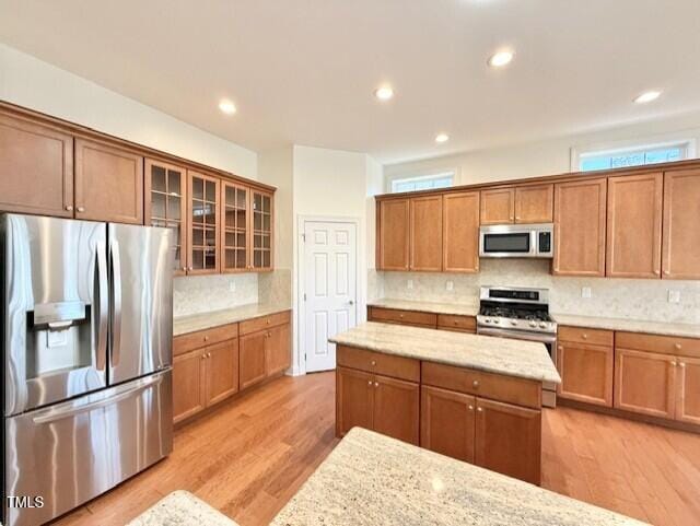 kitchen with brown cabinetry, stainless steel appliances, and light wood-type flooring