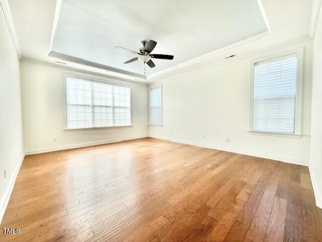 unfurnished room with ceiling fan, light wood-type flooring, a raised ceiling, and ornamental molding