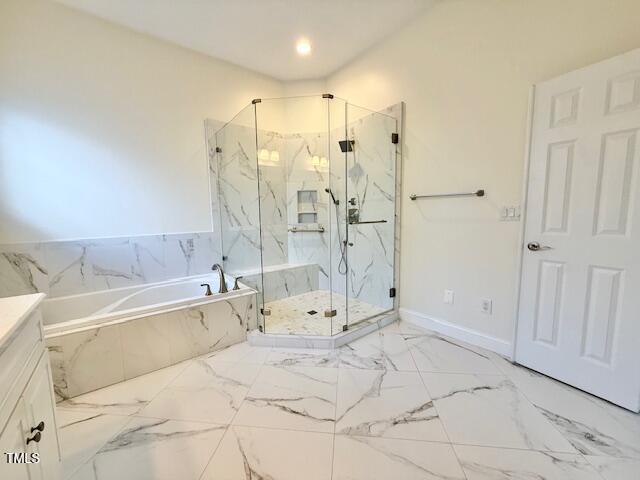 bathroom with a marble finish shower, marble finish floor, baseboards, and a garden tub