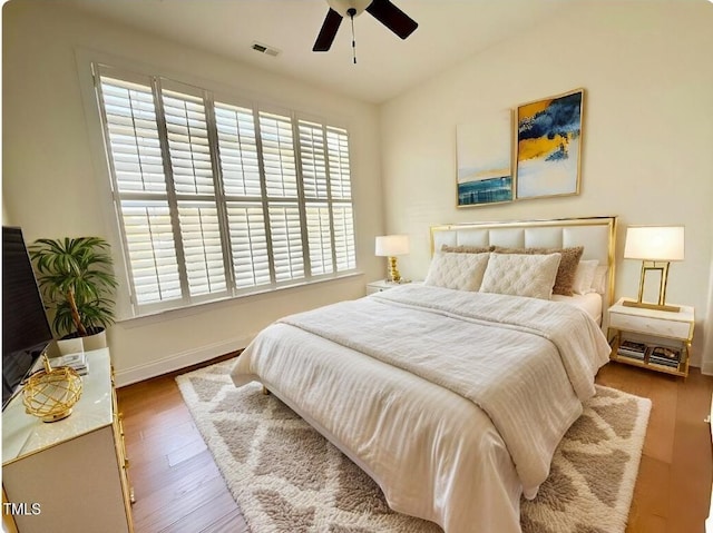 bedroom with visible vents, baseboards, wood finished floors, and a ceiling fan