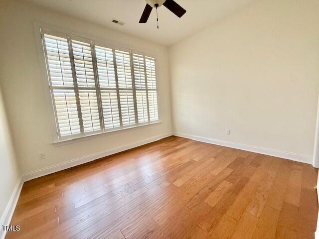 empty room featuring light wood-style flooring, a ceiling fan, and baseboards