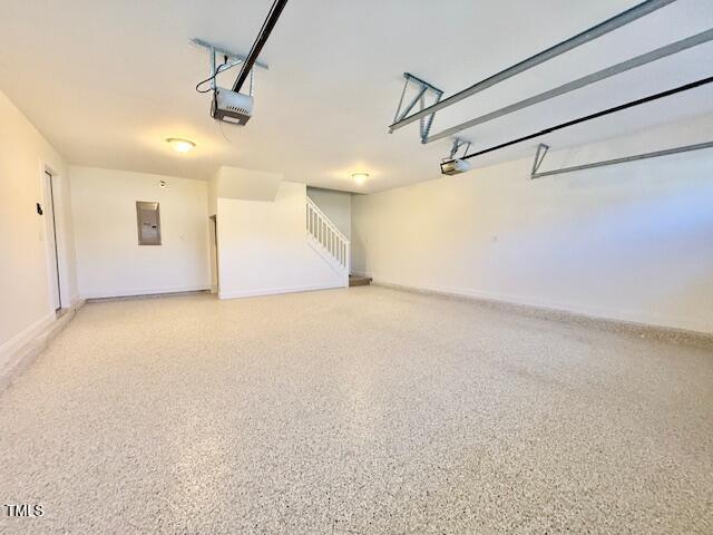 garage with electric panel, a garage door opener, and baseboards