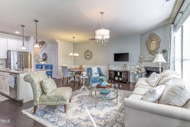 living area featuring a chandelier, dark wood-style flooring, a fireplace, and visible vents