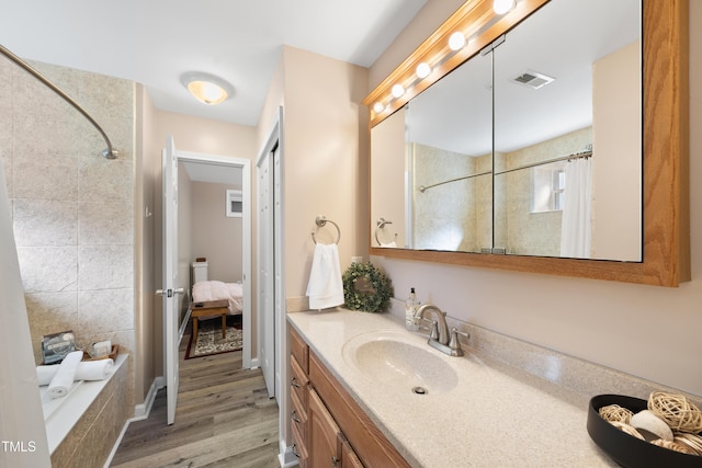 full bathroom featuring tiled shower / bath, wood finished floors, vanity, and visible vents