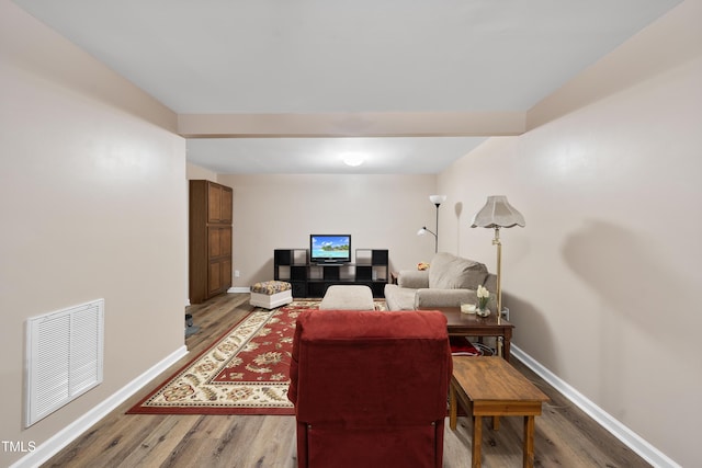 living room featuring baseboards, visible vents, and wood finished floors