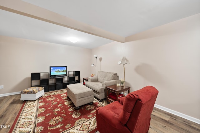 living room featuring wood finished floors, beam ceiling, and baseboards