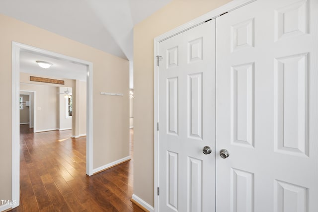 hallway with dark wood-style flooring and baseboards