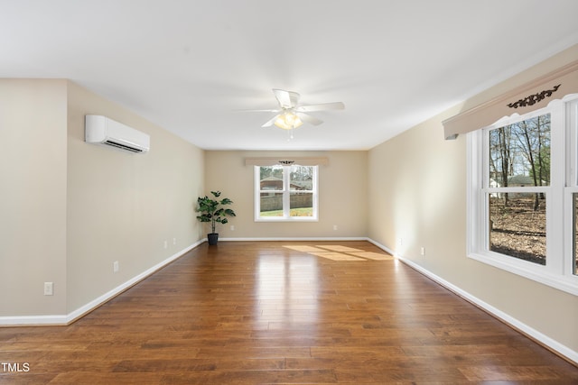 empty room with ceiling fan, a wall mounted air conditioner, wood finished floors, and baseboards