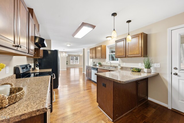 kitchen featuring stainless steel appliances, a sink, a peninsula, light wood-type flooring, and under cabinet range hood