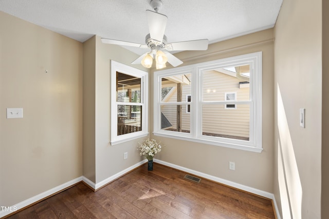 unfurnished dining area with a textured ceiling, a ceiling fan, visible vents, baseboards, and hardwood / wood-style floors