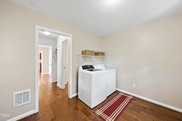 clothes washing area with hardwood / wood-style flooring, laundry area, visible vents, baseboards, and washer and clothes dryer