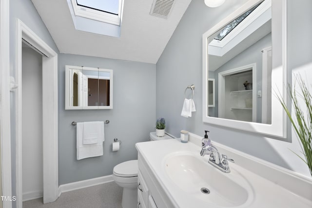 bathroom with vaulted ceiling with skylight, toilet, visible vents, vanity, and baseboards