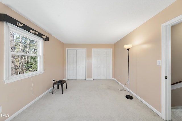 unfurnished bedroom featuring carpet floors, baseboards, and multiple closets