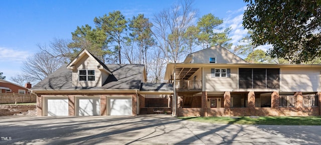 view of front facade with driveway, brick siding, an attached garage, and a balcony