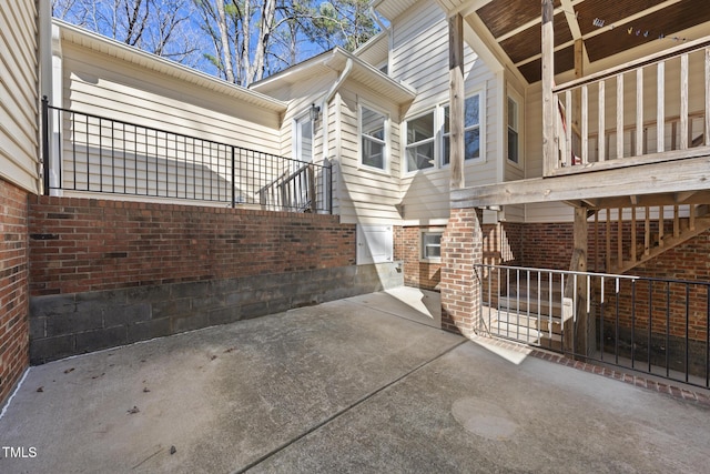 view of property exterior with brick siding and a patio