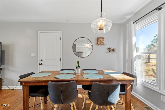 dining space with baseboards, light wood-style flooring, and a healthy amount of sunlight