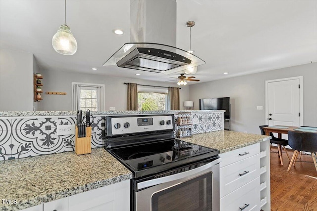 kitchen with light stone counters, white cabinetry, island range hood, wood finished floors, and stainless steel electric range