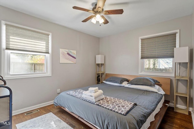 bedroom featuring multiple windows, wood finished floors, visible vents, and baseboards