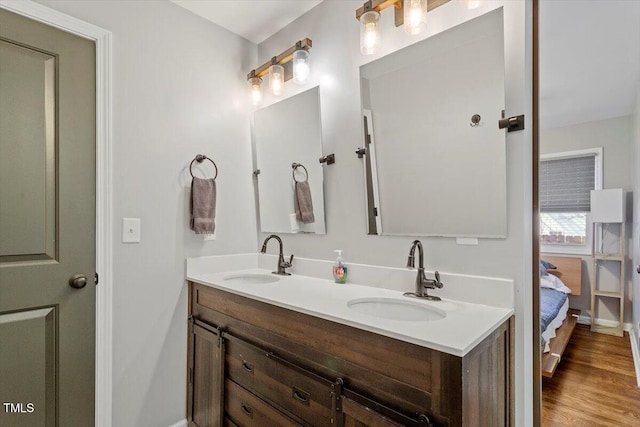 bathroom featuring double vanity, wood finished floors, a sink, and connected bathroom