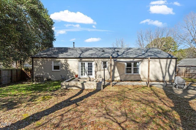 back of house with french doors, brick siding, central air condition unit, a lawn, and a fenced backyard