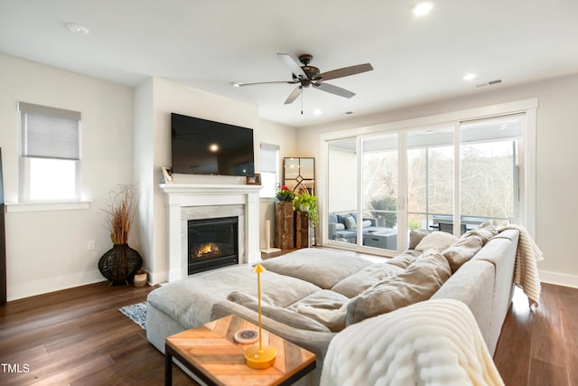 living room featuring baseboards, visible vents, dark wood-type flooring, and a glass covered fireplace