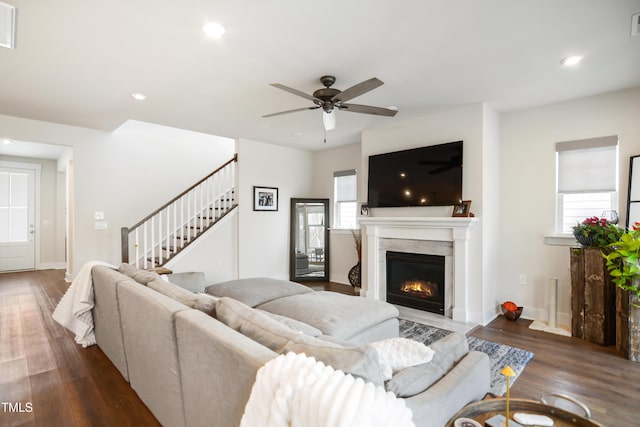 living area featuring a glass covered fireplace, stairway, recessed lighting, and wood finished floors