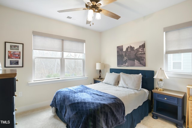 bedroom featuring baseboards, visible vents, a ceiling fan, and light colored carpet