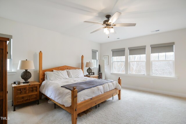 carpeted bedroom featuring a ceiling fan, visible vents, and baseboards