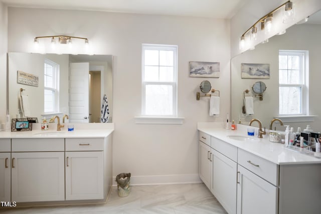 full bathroom featuring a wealth of natural light, two vanities, and a sink