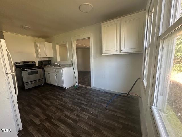kitchen with electric stove, black microwave, white cabinets, freestanding refrigerator, and dark wood finished floors