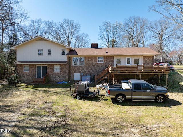 back of house featuring brick siding, a deck, a chimney, and a lawn