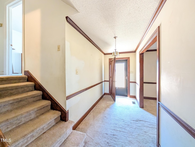 hallway featuring baseboards, ornamental molding, stairs, a textured ceiling, and light carpet