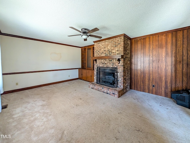 unfurnished living room with a textured ceiling, carpet, a fireplace, and ornamental molding