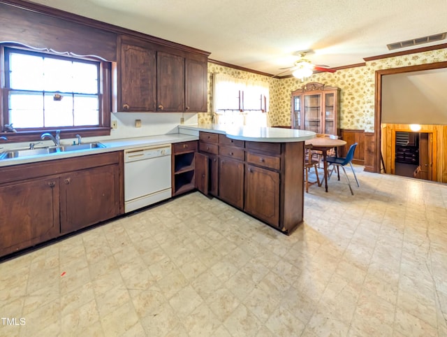 kitchen featuring a wainscoted wall, light floors, dishwasher, and wallpapered walls