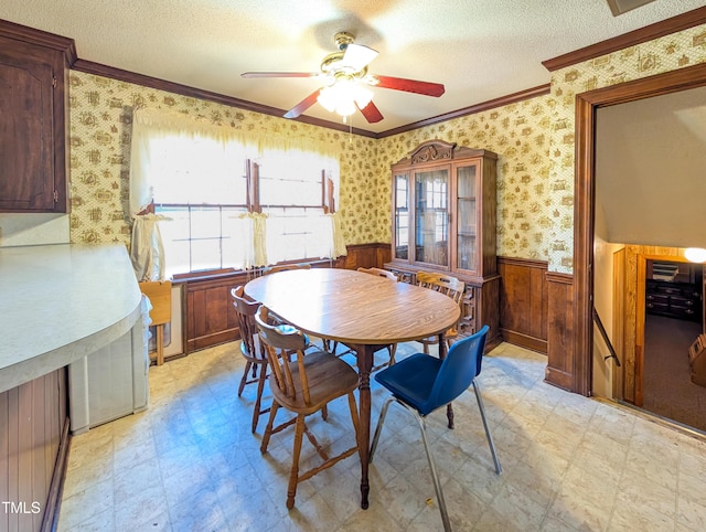 dining room featuring wallpapered walls, light floors, a wainscoted wall, and a textured ceiling