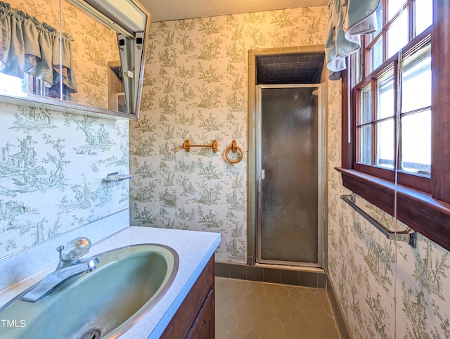 full bath featuring wallpapered walls, a stall shower, tile patterned floors, a textured ceiling, and vanity