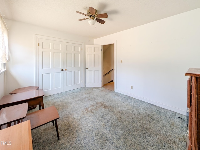 carpeted bedroom featuring ceiling fan, baseboards, a closet, and a textured ceiling