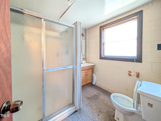 full bath featuring a stall shower, toilet, concrete block wall, and vanity