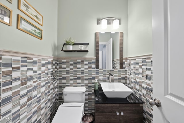 bathroom with a wainscoted wall, vanity, and toilet