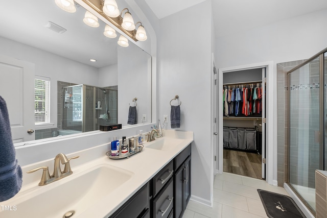 bathroom featuring double vanity, a stall shower, and a sink