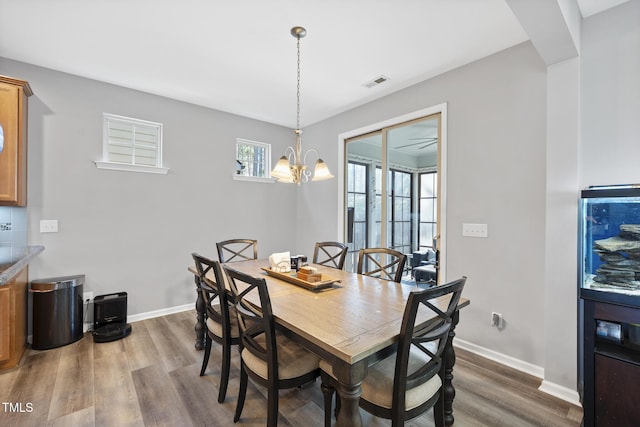 dining area with a chandelier, visible vents, baseboards, and wood finished floors