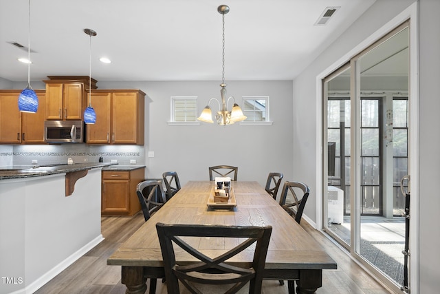 dining room with baseboards, visible vents, light wood-style floors, a notable chandelier, and recessed lighting