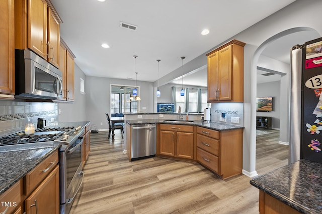 kitchen with visible vents, light wood-style flooring, appliances with stainless steel finishes, brown cabinets, and a sink