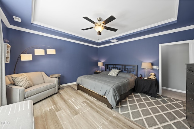 bedroom featuring crown molding, a tray ceiling, wood finished floors, and baseboards