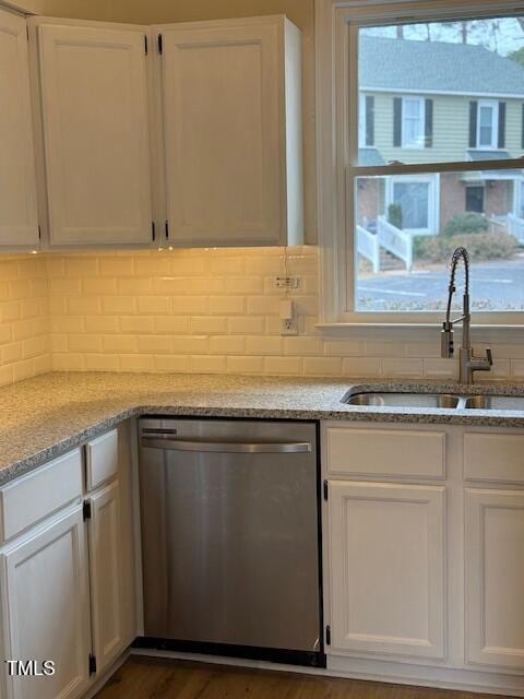 kitchen featuring a sink, tasteful backsplash, stainless steel dishwasher, and white cabinetry