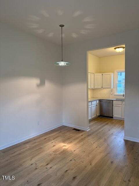 unfurnished dining area with a sink, baseboards, and wood finished floors