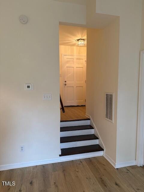 stairs featuring visible vents, baseboards, and wood finished floors