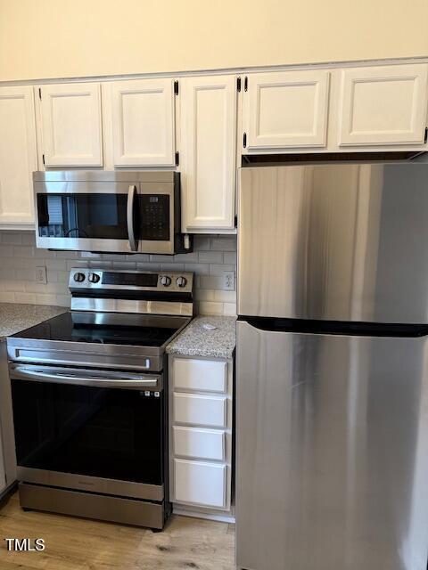 kitchen featuring white cabinetry, light wood-style flooring, tasteful backsplash, and appliances with stainless steel finishes