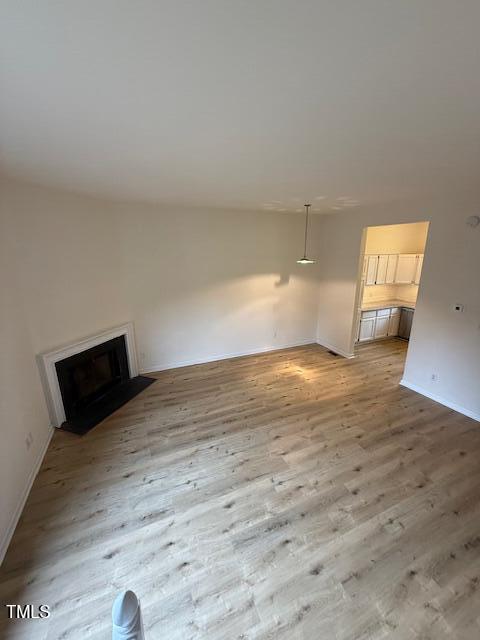 unfurnished living room featuring baseboards, light wood-style floors, and a fireplace