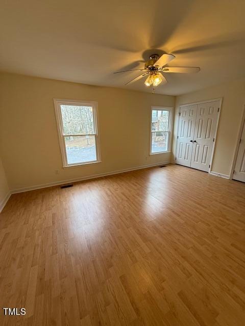 unfurnished bedroom with visible vents, light wood-style flooring, a ceiling fan, and baseboards